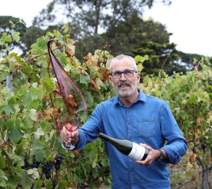 Leigh Clarnette from Clarnette Wines standing in a vineyard tossing red wine from a wine glass